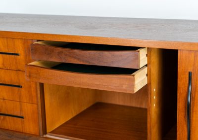 Danish highboard in teak, 1960s. A beautiful mid-century piece crafted in rich teak and standing on oak base, featuring lots of storage space and contrasting black handels. The highboard showcases a warm, natural woodgrain, sleek lines, and distinctive handles. It is in excellent condition with some minor using traces on the top.