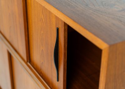 Danish highboard in teak, 1960s. A beautiful mid-century piece crafted in rich teak and standing on oak base, featuring lots of storage space and contrasting black handels. The highboard showcases a warm, natural woodgrain, sleek lines, and distinctive handles. It is in excellent condition with some minor using traces on the top.