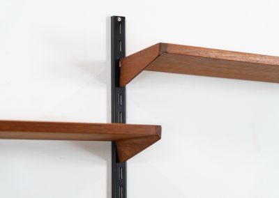 Beautiful wall-unit by Kai Kristiansen for FM Møbler (Denmark, 1960s). Just a stunning shelving system featuring three black metal wall mounts, six normal shelves and one extra wide shelve which can also be used as a small desk. The modular system allows for endless configuration possibilities, enabling you to arrange the pieces to suit your personal taste and space. The wall-unit remains in excellent condition!