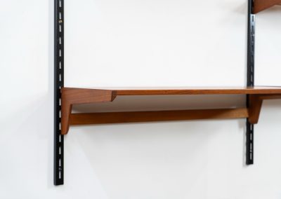 Beautiful wall-unit by Kai Kristiansen for FM Møbler (Denmark, 1960s). Just a stunning shelving system featuring three black metal wall mounts, six normal shelves and one extra wide shelve which can also be used as a small desk. The modular system allows for endless configuration possibilities, enabling you to arrange the pieces to suit your personal taste and space. The wall-unit remains in excellent condition!