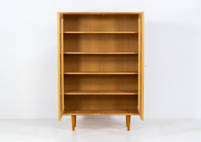 Oak showcase by WK Möbel (Germany, 1970s). This beautiful showcase features a stunning aged oak woodgrain and has two handle-less doors with glass panels, providing a clear view of the interior. Inside, there are four adjustable shelves, offering lots of storage options. It is in very good condition and labeled by maker.