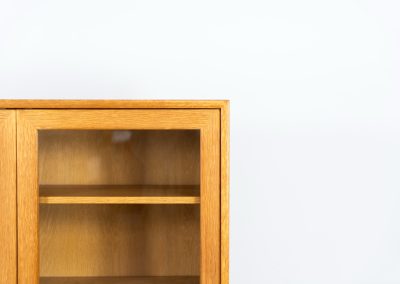 Oak showcase by WK Möbel (Germany, 1970s). This beautiful showcase features a stunning aged oak woodgrain and has two handle-less doors with glass panels, providing a clear view of the interior. Inside, there are four adjustable shelves, offering lots of storage options. It is in very good condition and labeled by maker.