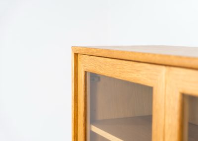 Oak showcase by WK Möbel (Germany, 1970s). This beautiful showcase features a stunning aged oak woodgrain and has two handle-less doors with glass panels, providing a clear view of the interior. Inside, there are four adjustable shelves, offering lots of storage options. It is in very good condition and labeled by maker.