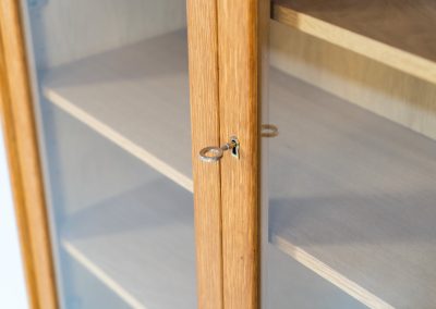 Oak showcase by WK Möbel (Germany, 1970s). This beautiful showcase features a stunning aged oak woodgrain and has two handle-less doors with glass panels, providing a clear view of the interior. Inside, there are four adjustable shelves, offering lots of storage options. It is in very good condition and labeled by maker.