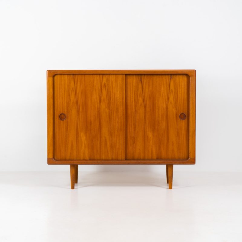 Mid-size cabinet in teak by CFC Silkeborg (Denmark, 1960s). The cabinet is made out of teak and features stunning organic shapes, round inset handles and and a mesmerizing woodgrain! It offers two sliding doors with on the inside two large adjustable shelves, one small adjustable shelves and two drawers. The interior of the cabinet features two discreet slots, designed for air ventilation and optional cable management. This piece presents itself in mint condition with no damages or significant using traces. It is labeled on the back.
