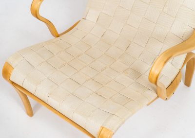 “Miranda” easy chair by Bruno Mathsson Design Studio (Sweden, 1970s). Originally designed by Bruno Mathsson in 1941, this exceptional “Miranda” easy chair was manufactured in the 1970s. It features a beautifully curved, molded beech plywood frame with a linen webbing seat and an adjustable headrest, suspended by leather straps. The chair is in good vintage condition, showing signs of use such as marks, fabric fraying, and some damage to the wood, all of which add to its authentic character. Marked by maker.