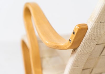 “Miranda” easy chair by Bruno Mathsson Design Studio (Sweden, 1970s). Originally designed by Bruno Mathsson in 1941, this exceptional “Miranda” easy chair was manufactured in the 1970s. It features a beautifully curved, molded beech plywood frame with a linen webbing seat and an adjustable headrest, suspended by leather straps. The chair is in good vintage condition, showing signs of use such as marks, fabric fraying, and some damage to the wood, all of which add to its authentic character. Marked by maker.