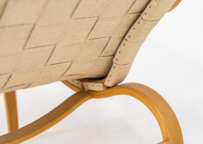 “Miranda” easy chair by Bruno Mathsson Design Studio (Sweden, 1970s). Originally designed by Bruno Mathsson in 1941, this exceptional “Miranda” easy chair was manufactured in the 1970s. It features a beautifully curved, molded beech plywood frame with a linen webbing seat and an adjustable headrest, suspended by leather straps. The chair is in good vintage condition, showing signs of use such as marks, fabric fraying, and some damage to the wood, all of which add to its authentic character. Marked by maker.