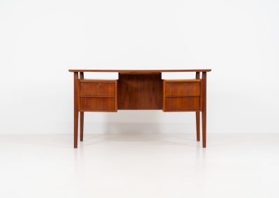 Freestanding desk by Gunnar Nielsen Tibergaard (Denmark, 1960s). A beautifully designed and elegant teak desk from the 1960s, featuring four drawers and a finished back that allows it to stand freely in any space. The rear side includes an open storage area/bookcase and a cabinet with a drop-down leaf. The desk is in very good condition with one very small chip in the wood on the right back-corner as shown on the pictures.