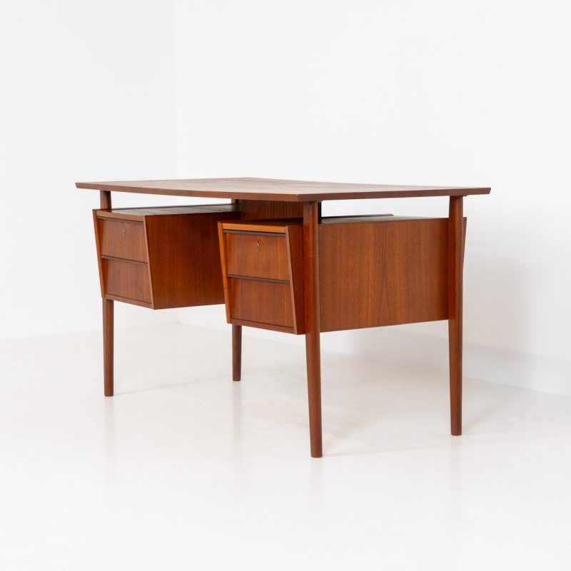 Freestanding desk by Gunnar Nielsen Tibergaard (Denmark, 1960s). A beautifully designed and elegant teak desk from the 1960s, featuring four drawers and a finished back that allows it to stand freely in any space. The rear side includes an open storage area/bookcase and a cabinet with a drop-down leaf. The desk is in very good condition with one very small chip in the wood on the right back-corner as shown on the pictures.