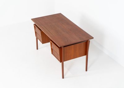 Freestanding desk by Gunnar Nielsen Tibergaard (Denmark, 1960s). A beautifully designed and elegant teak desk from the 1960s, featuring four drawers and a finished back that allows it to stand freely in any space. The rear side includes an open storage area/bookcase and a cabinet with a drop-down leaf. The desk is in very good condition with one very small chip in the wood on the right back-corner as shown on the pictures.
