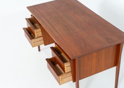 Freestanding desk by Gunnar Nielsen Tibergaard (Denmark, 1960s). A beautifully designed and elegant teak desk from the 1960s, featuring four drawers and a finished back that allows it to stand freely in any space. The rear side includes an open storage area/bookcase and a cabinet with a drop-down leaf. The desk is in very good condition with one very small chip in the wood on the right back-corner as shown on the pictures.
