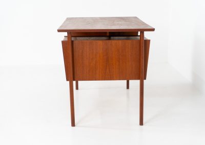 Freestanding desk by Gunnar Nielsen Tibergaard (Denmark, 1960s). A beautifully designed and elegant teak desk from the 1960s, featuring four drawers and a finished back that allows it to stand freely in any space. The rear side includes an open storage area/bookcase and a cabinet with a drop-down leaf. The desk is in very good condition with one very small chip in the wood on the right back-corner as shown on the pictures.