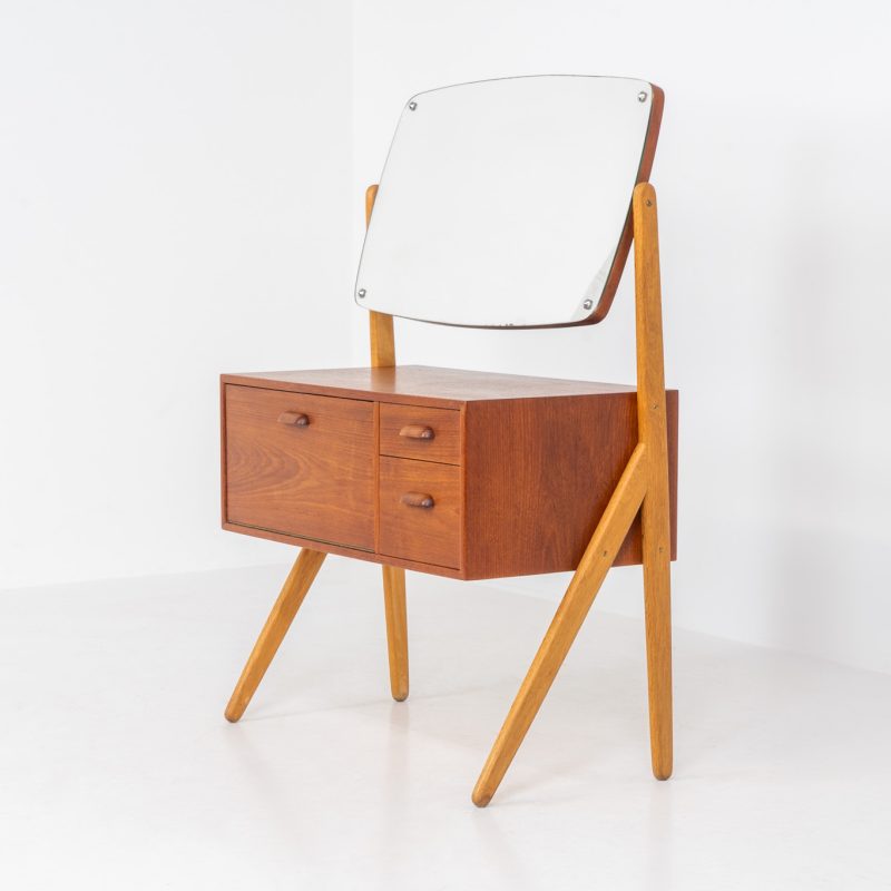 Iconic dressing table by Ølholm Møbelfabrik (Denmark, 1960s). This highly elegant piece is a renowned icon and features organic lines and impeccable craftsmanship! It has a teak cabinet with two drawers and a door, solid oak Y-shaped legs and a beautiful tiltable oval mirror. It is designed as a dressing table but can be used in many settings. It is in mint condition!