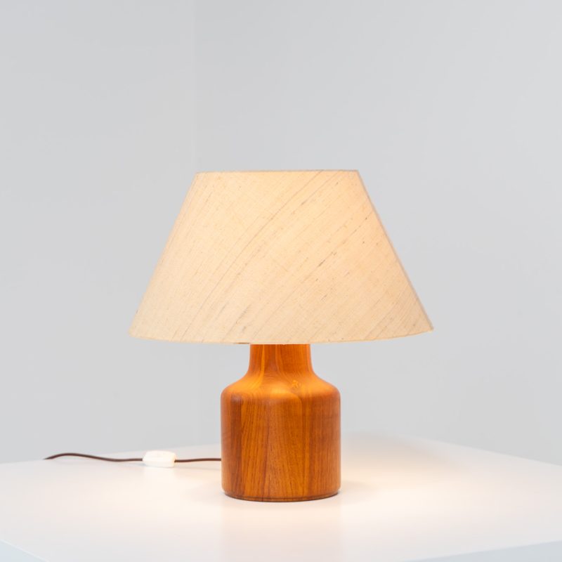 Solid teak table lamp by Kirk Copenhagen (Denmark, 1960s). A beautifully sculpted table lamp crafted from solid teak. It features a generous lampshade made from wild silk, adding a soft, organic texture to its refined silhouette. The lamp is in very good vintage condition.