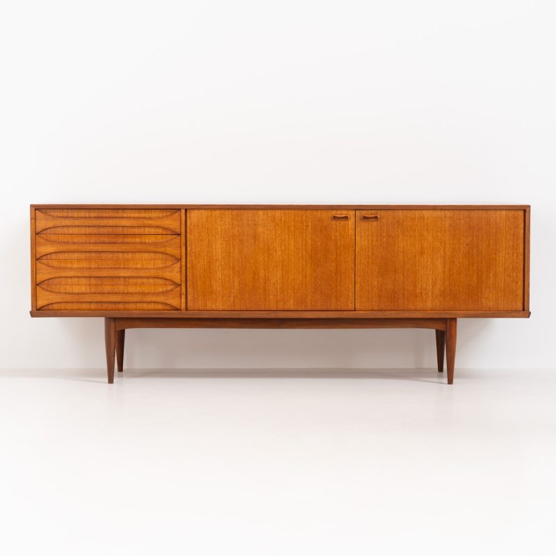 Stunning “Astrid” sideboard by Oswald Vermaercke for V-Form (Belgium, 1950s). An amazing and hard to find piece with a lot of details and highly sought after dimensions. Its crafted out of teak and features two large folding doors and four beautifully sculpted elliptical drawers. It is in good and original condition, but has age related using traces like some scratches or a dark spot on the right side as shown on the pictures. It is labeled.