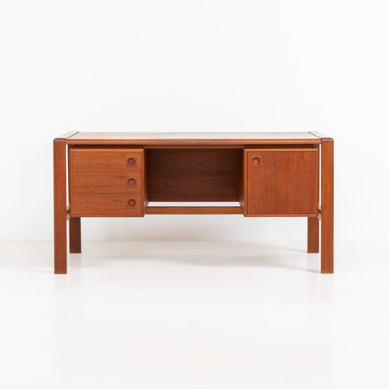 Rare executive writing desk by H.P. Hansen (Denmark, 1950s). This large and exceptionally beautiful piece is a true example of top-quality Danish craftsmanship. Made from solid teak, it showcases elegant aesthetics with softly rounded edges and sculptural inset handles. The spacious desktop highlights a striking wood grain and is complemented by three drawers, a cabinet, and two open shelves at the back. The desk is finished on both sides, making it an ideal statement piece for placement in the center of a room. It is in excellent condition, with only minor discoloration on the top and light signs of use on the drawers.