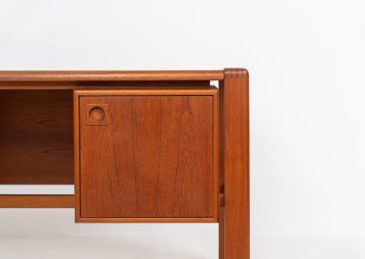 Rare executive writing desk by H.P. Hansen (Denmark, 1950s). This large and exceptionally beautiful piece is a true example of top-quality Danish craftsmanship. Made from solid teak, it showcases elegant aesthetics with softly rounded edges and sculptural inset handles. The spacious desktop highlights a striking wood grain and is complemented by three drawers, a cabinet, and two open shelves at the back. The desk is finished on both sides, making it an ideal statement piece for placement in the center of a room. It is in excellent condition, with only minor discoloration on the top and light signs of use on the drawers.
