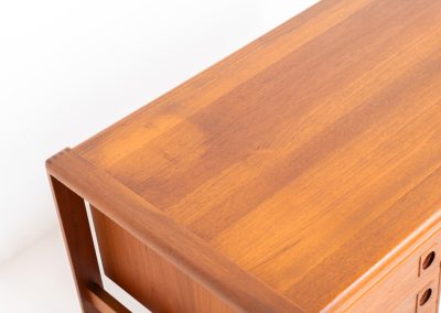 Rare executive writing desk by H.P. Hansen (Denmark, 1950s). This large and exceptionally beautiful piece is a true example of top-quality Danish craftsmanship. Made from solid teak, it showcases elegant aesthetics with softly rounded edges and sculptural inset handles. The spacious desktop highlights a striking wood grain and is complemented by three drawers, a cabinet, and two open shelves at the back. The desk is finished on both sides, making it an ideal statement piece for placement in the center of a room. It is in excellent condition, with only minor discoloration on the top and light signs of use on the drawers.