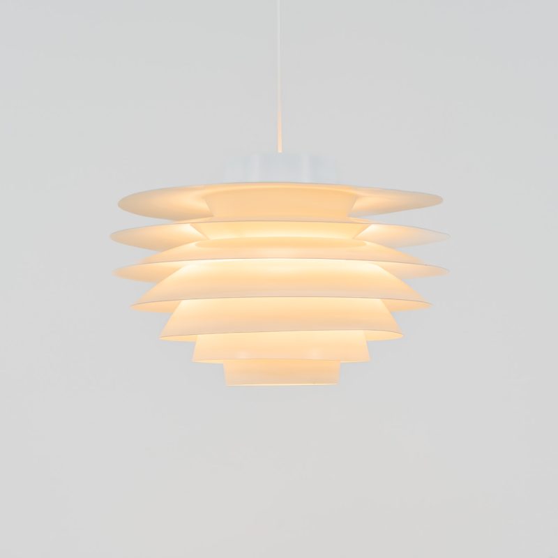 XL “Verona” pendant lights by Svend Middelboe for Nordisk Solar (Denmark, 1970s). A striking design classic featuring seven aluminium shades that gently diffuse light into a soft, ambient glow. The Verona is a perfect balance of form and function, its sculptural silhouette and calming illumination make it an elegant statement piece in any interior. This example is in good vintage condition, with some signs of age such as minor scuffs to the paint and a slight misalignment of the shades. It includes the original ceiling mount, allowing for direct installation to the ceiling without a visible cable.