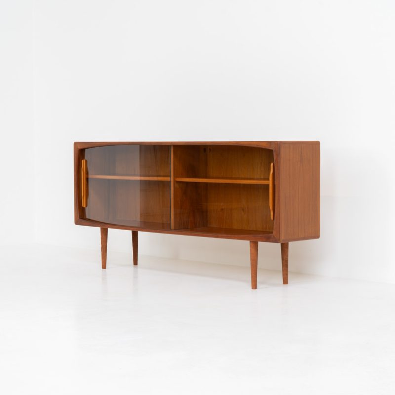 Lovely sideboard with glass doors by Svend Dyrlund (Denmark, 1960s). This elegant mid-century piece, crafted in teak, features beautifully rounded edges, sleek glass sliding doors, and refined wooden handles. Its timeless design combines style with functionality, offering lots of storage space with two adjustable shelves inside. This piece is in splendid condition!