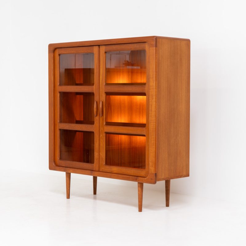 Stunning showcase by Svend Dyrlund (Denmark, 1960s). This exceptional piece features elegant doors with glass panels and beautifully crafted wooden handles, two adjustable shelves, and convenient backlights behind each shelf to highlight your displayed items. Made from rich teak with a natural woodgrain, it perfectly combines functionality with the timeless characteristic of Danish modern design. In splendid condition & labeled by maker.