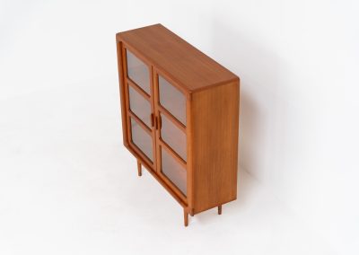 Stunning showcase by Svend Dyrlund (Denmark, 1960s). This exceptional piece features elegant doors with glass panels and beautifully crafted wooden handles, two adjustable shelves, and convenient backlights behind each shelf to highlight your displayed items. Made from rich teak with a natural woodgrain, it perfectly combines functionality with the timeless characteristic of Danish modern design. In splendid condition & labeled by maker.