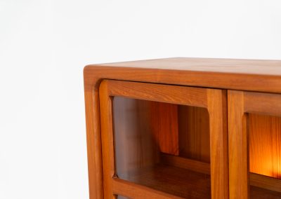 Stunning showcase by Svend Dyrlund (Denmark, 1960s). This exceptional piece features elegant doors with glass panels and beautifully crafted wooden handles, two adjustable shelves, and convenient backlights behind each shelf to highlight your displayed items. Made from rich teak with a natural woodgrain, it perfectly combines functionality with the timeless characteristic of Danish modern design. In splendid condition & labeled by maker.