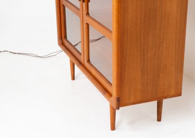 Stunning showcase by Svend Dyrlund (Denmark, 1960s). This exceptional piece features elegant doors with glass panels and beautifully crafted wooden handles, two adjustable shelves, and convenient backlights behind each shelf to highlight your displayed items. Made from rich teak with a natural woodgrain, it perfectly combines functionality with the timeless characteristic of Danish modern design. In splendid condition & labeled by maker.