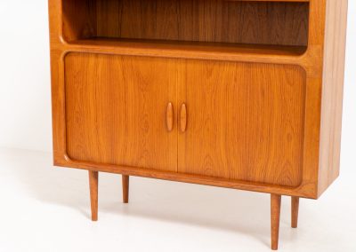 Beautiful bookcase in teak by Svend Dyrlund with tambour doors (Denmark, 1960s). This bookcase perfectly combines organic shapes and loads of details, like the tambour sliding doors, the beautiful handles or the bulky shelves, which are adjustable in height. It offers lots of storage space! In mint condition!