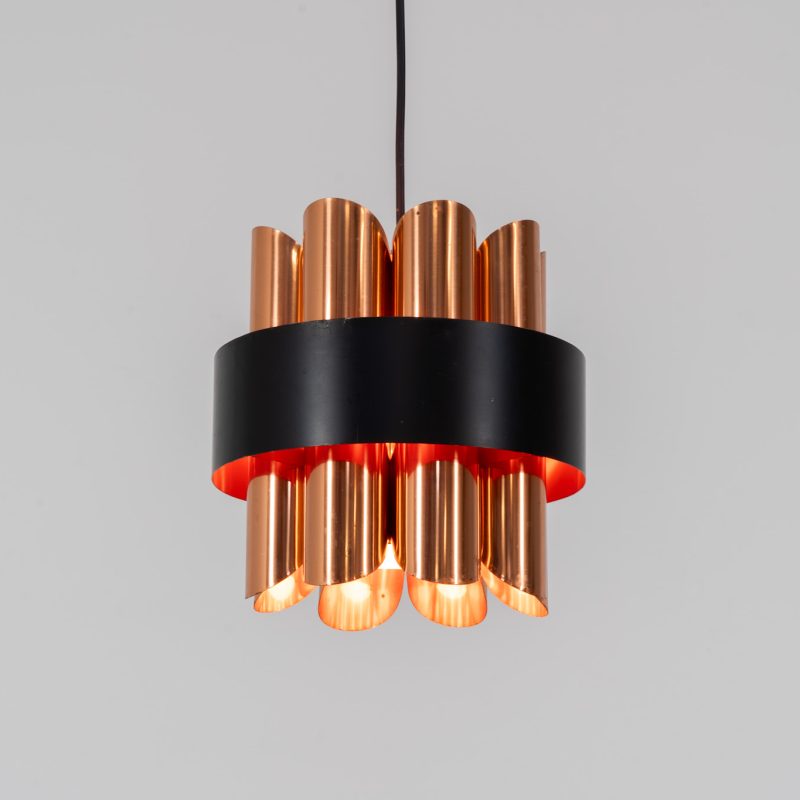 Stunning copper pendant light by Werner Schou for Coronell (Denmark, 1970s). It is made out of two tiers of brushed copper plates and a black halo which is lacquered orange on the inside. The combination of the orange and copper gives a striking rich light glow when turned on. In very good condition with a beautiful patina, a true eye catcher!