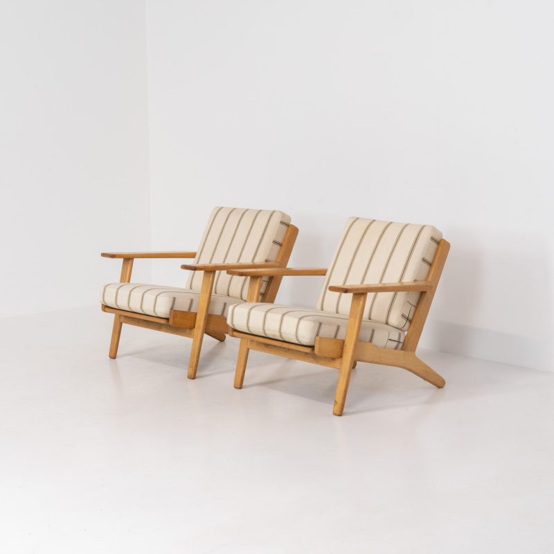 Pair of Early GE-290 lounge chairs in oak by Hans J. Wegner for Getama (Denmark, 1953). A hard to find design classic by the great Hans Wegner. They feature the original wool cushions and are in untouched vintage condition with some visible stains on the wool and scratches on the wood. Marked by maker.