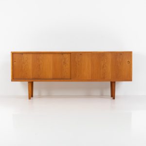 Rare and important RY26 sideboard by Hans J. Wegner for Ry Møbler (Denmark, 1950s). This incredible piece is composed of delicately grained oak with a stunning honey hued stain. It contains two large sliding doors with round inset handles, adjustable shelves and four modular drawers on the inside. This hard to find piece remains in very good vintage condition. It is designed by the the renowned Hans J. Wegner who won multiple awards and honors throughout his carreer.
