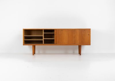 Rare and important RY26 sideboard by Hans J. Wegner for Ry Møbler (Denmark, 1950s). This incredible piece is composed of delicately grained oak with a stunning honey hued stain. It contains two large sliding doors with round inset handles, adjustable shelves and four modular drawers on the inside. This hard to find piece remains in very good vintage condition. It is designed by the the renowned Hans J. Wegner who won multiple awards and honors throughout his carreer.