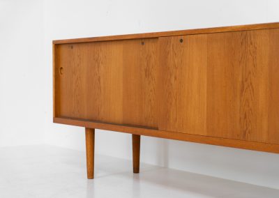 Rare and important RY26 sideboard by Hans J. Wegner for Ry Møbler (Denmark, 1950s). This incredible piece is composed of delicately grained oak with a stunning honey hued stain. It contains two large sliding doors with round inset handles, adjustable shelves and four modular drawers on the inside. This hard to find piece remains in very good vintage condition. It is designed by the the renowned Hans J. Wegner who won multiple awards and honors throughout his carreer.