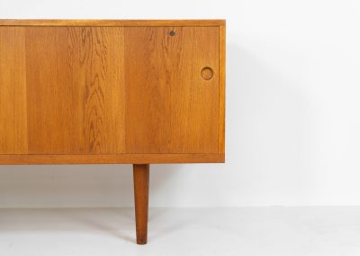Rare and important RY26 sideboard by Hans J. Wegner for Ry Møbler (Denmark, 1950s). This incredible piece is composed of delicately grained oak with a stunning honey hued stain. It contains two large sliding doors with round inset handles, adjustable shelves and four modular drawers on the inside. This hard to find piece remains in very good vintage condition. It is designed by the the renowned Hans J. Wegner who won multiple awards and honors throughout his carreer.