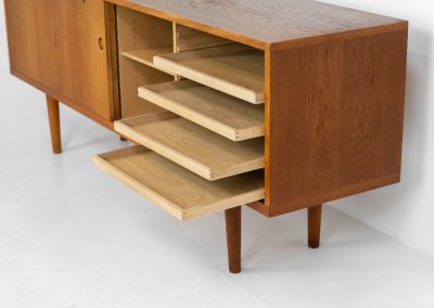 Rare and important RY26 sideboard by Hans J. Wegner for Ry Møbler (Denmark, 1950s). This incredible piece is composed of delicately grained oak with a stunning honey hued stain. It contains two large sliding doors with round inset handles, adjustable shelves and four modular drawers on the inside. This hard to find piece remains in very good vintage condition. It is designed by the the renowned Hans J. Wegner who won multiple awards and honors throughout his carreer.