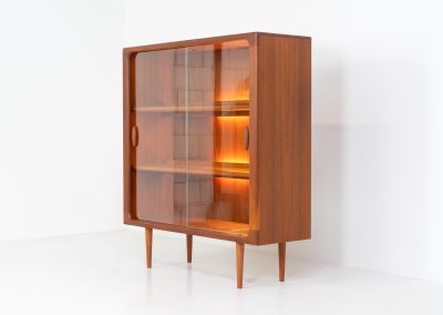 Stunning showcase by Svend Dyrlund (Denmark, 1960s). This exceptional piece features elegant glass doors with beautifully crafted wooden handles, two adjustable shelves, and convenient backlights behind each shelf to highlight your displayed items. Made from rich teak with a natural woodgrain, it perfectly combines functionality with the timeless characteristic of Danish modern design. In splendid condition.