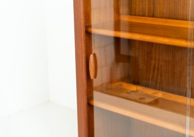 Stunning showcase by Svend Dyrlund (Denmark, 1960s). This exceptional piece features elegant glass doors with beautifully crafted wooden handles, two adjustable shelves, and convenient backlights behind each shelf to highlight your displayed items. Made from rich teak with a natural woodgrain, it perfectly combines functionality with the timeless characteristic of Danish modern design. In splendid condition.
