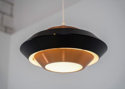 Striking copper & black pendant light (Denmark, 1960s). This striking vintage pendant lamp features a refined combination of brushed copper and deep black lacquered metal. Its sculptural, UFO-inspired silhouette creates a warm, atmospheric glow while adding a bold design statement to any interior. The lamp is in very good condition!