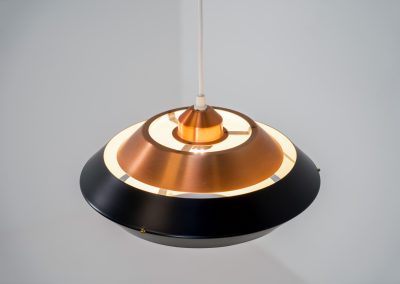 Striking copper & black pendant light (Denmark, 1960s). This striking vintage pendant lamp features a refined combination of brushed copper and deep black lacquered metal. Its sculptural, UFO-inspired silhouette creates a warm, atmospheric glow while adding a bold design statement to any interior. The lamp is in very good condition!