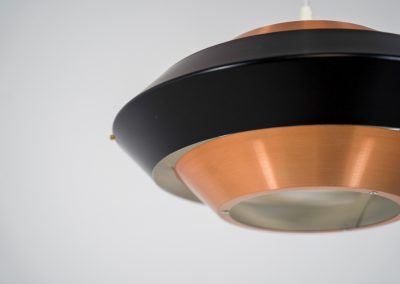 Striking copper & black pendant light (Denmark, 1960s). This striking vintage pendant lamp features a refined combination of brushed copper and deep black lacquered metal. Its sculptural, UFO-inspired silhouette creates a warm, atmospheric glow while adding a bold design statement to any interior. The lamp is in very good condition!