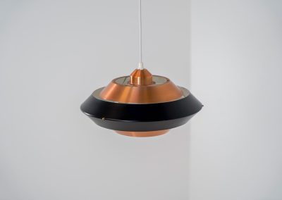 Striking copper & black pendant light (Denmark, 1960s). This striking vintage pendant lamp features a refined combination of brushed copper and deep black lacquered metal. Its sculptural, UFO-inspired silhouette creates a warm, atmospheric glow while adding a bold design statement to any interior. The lamp is in very good condition!