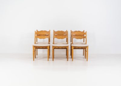 Set of 6 brutalist chairs in oak by Henning Kjaernulf (Denmark, 1970s). These brutalist dining chairs by Henning Kjaernulf have oak frames that display a beautifully matured patina that highlights the natural character of the wood. The seats have been newly upholstered in an off-white structured fabric, adding a fresh and refined contrast to the robust design. A timeless and highly collectible set that brings both presence and warmth to any interior.