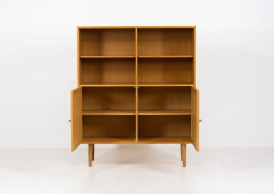 Oak bookcase by Rud Thygesen & Johnny Sørensen for HG furniture (Denmark, 1960s). It contains open shelves and two elegant doors with more shelves on the inside. The bookcase is in splendid condition.
