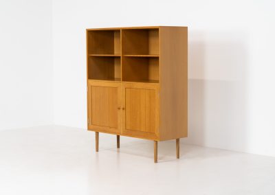 Oak bookcase by Rud Thygesen & Johnny Sørensen for HG furniture (Denmark, 1960s). It contains open shelves and two elegant doors with more shelves on the inside. The bookcase is in splendid condition.