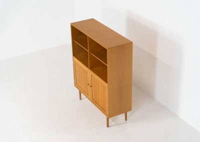 Oak bookcase by Rud Thygesen & Johnny Sørensen for HG furniture (Denmark, 1960s). It contains open shelves and two elegant doors with more shelves on the inside. The bookcase is in splendid condition.