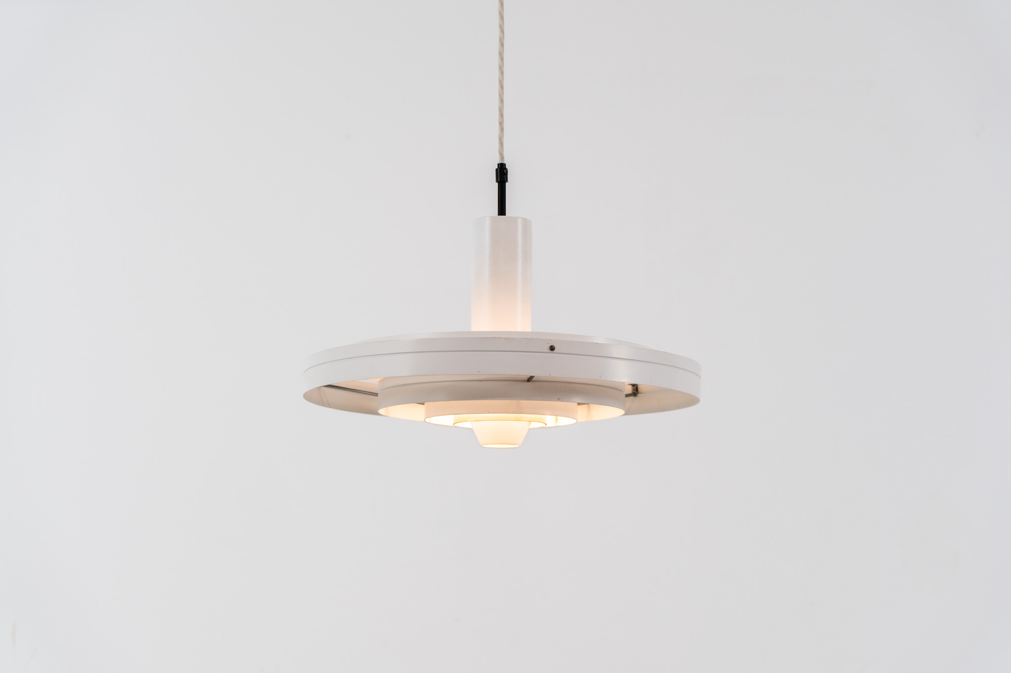 “Fibonacci” pendant light by Sophus Frandsen for Fog & Mørup (Denmark, 1960s). The Fibonacci lamp uses a gravity-guided sliding dip mechanism: the shade glides along the rail and naturally ‘dips’ into position, allowing effortless adjustment of light direction and intensity, a hallmark of Sophus Frandsen’s engineering-minded approach to lighting. The lamp is in amazing vintage condition with minor age related marks. Marked by maker.