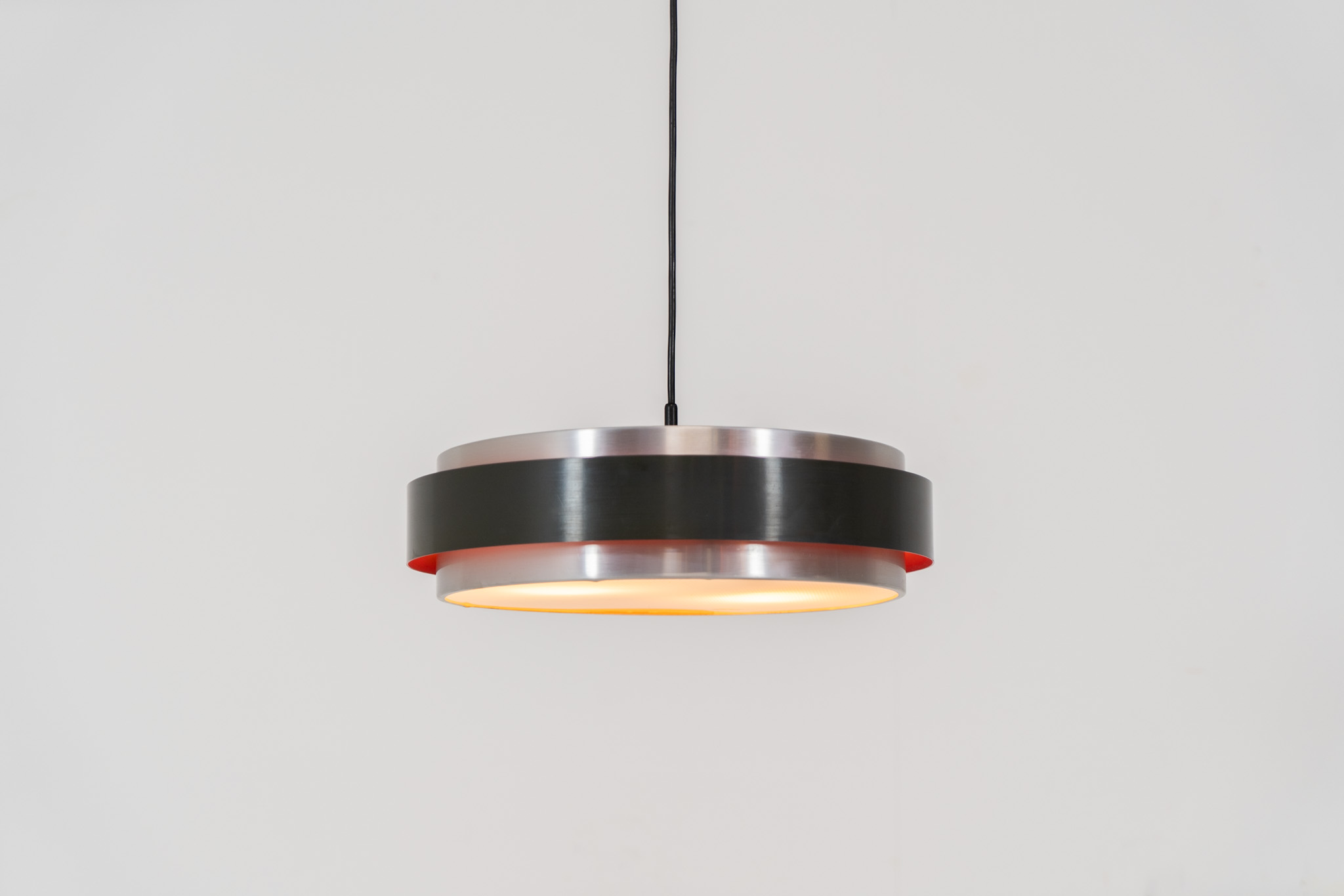 “Sera” pendant light by Jo Hammerborg for Fog & Mørup (Denmark, 1960s). A wonderful example of Danish modernism! This Sera pendel has a sleek, timeless and stunning appearance. Crafted with two brushed aluminium shades, a black lacquered halo and an acrylic light diffuser. The inside of the halo is lacquered in pink, which gives that extra dimension in the light dispersion when turned on. The lamp is in very good vintage condition!
