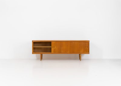 Exceptional sideboard by Henry W. Klein for Bramin in oak (Denmark, 1960s). This piece is a true masterpiece of Danish mid-century design. Crafted from high-quality materials, it showcases exquisite attention to detail, from the sculptural integrated handles to the beautifully crafted corner joints. The sideboard offers the perfect balance of aesthetics and functionality. It features two large sliding doors with adjustable shelves behind them and four drawers. The highboard is in very good condition and marked by maker.